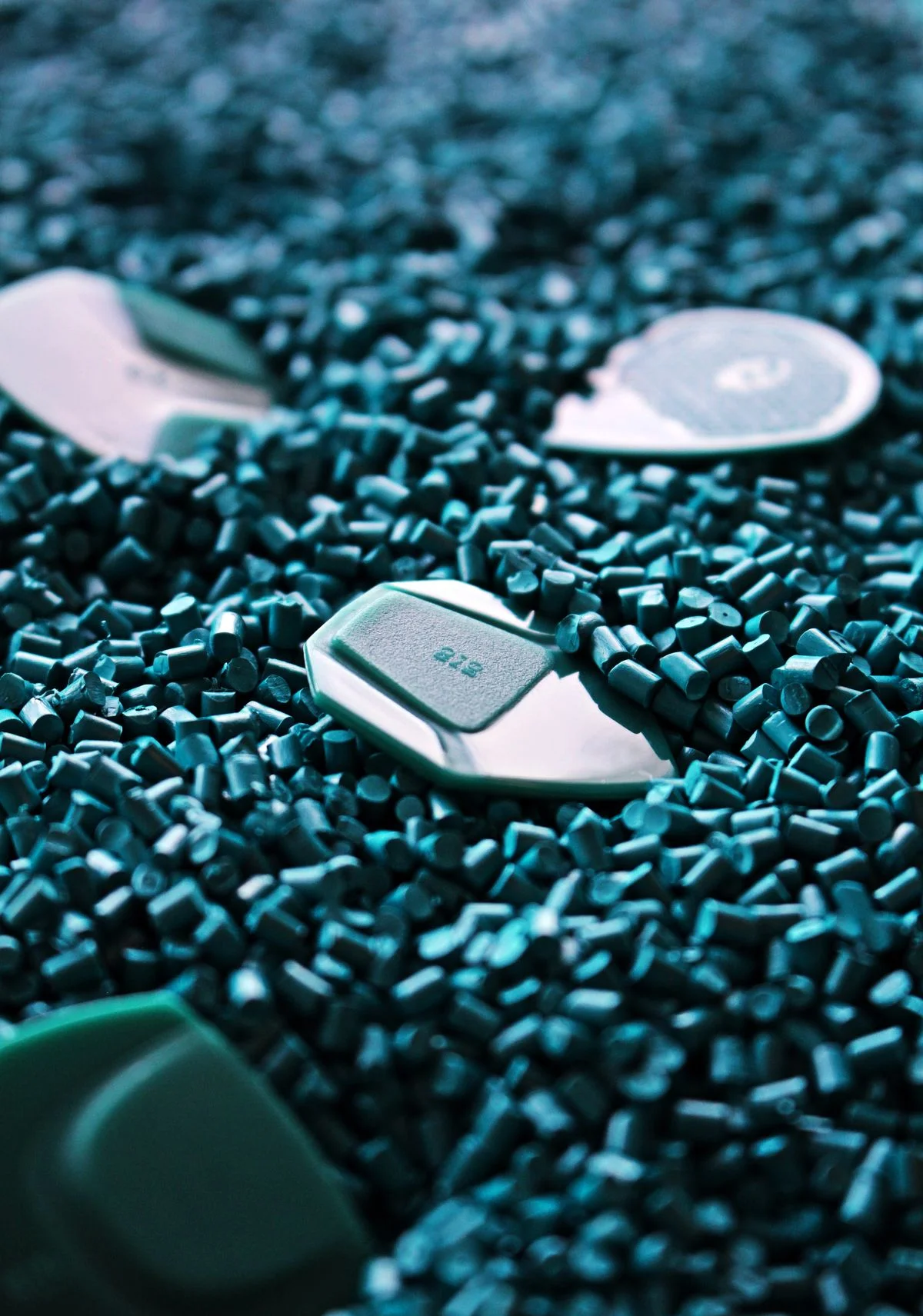 Gránulos de plástico cilíndricos uniformes de color verde azulado con tamaño y forma consistentes junto con componentes moldeados - Pexels

