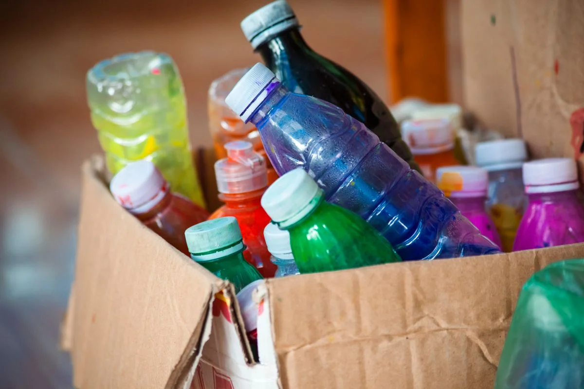 Botellas de plástico transparente en tonos verde, azul, naranja y rosa envasadas en cartón - Pexels

