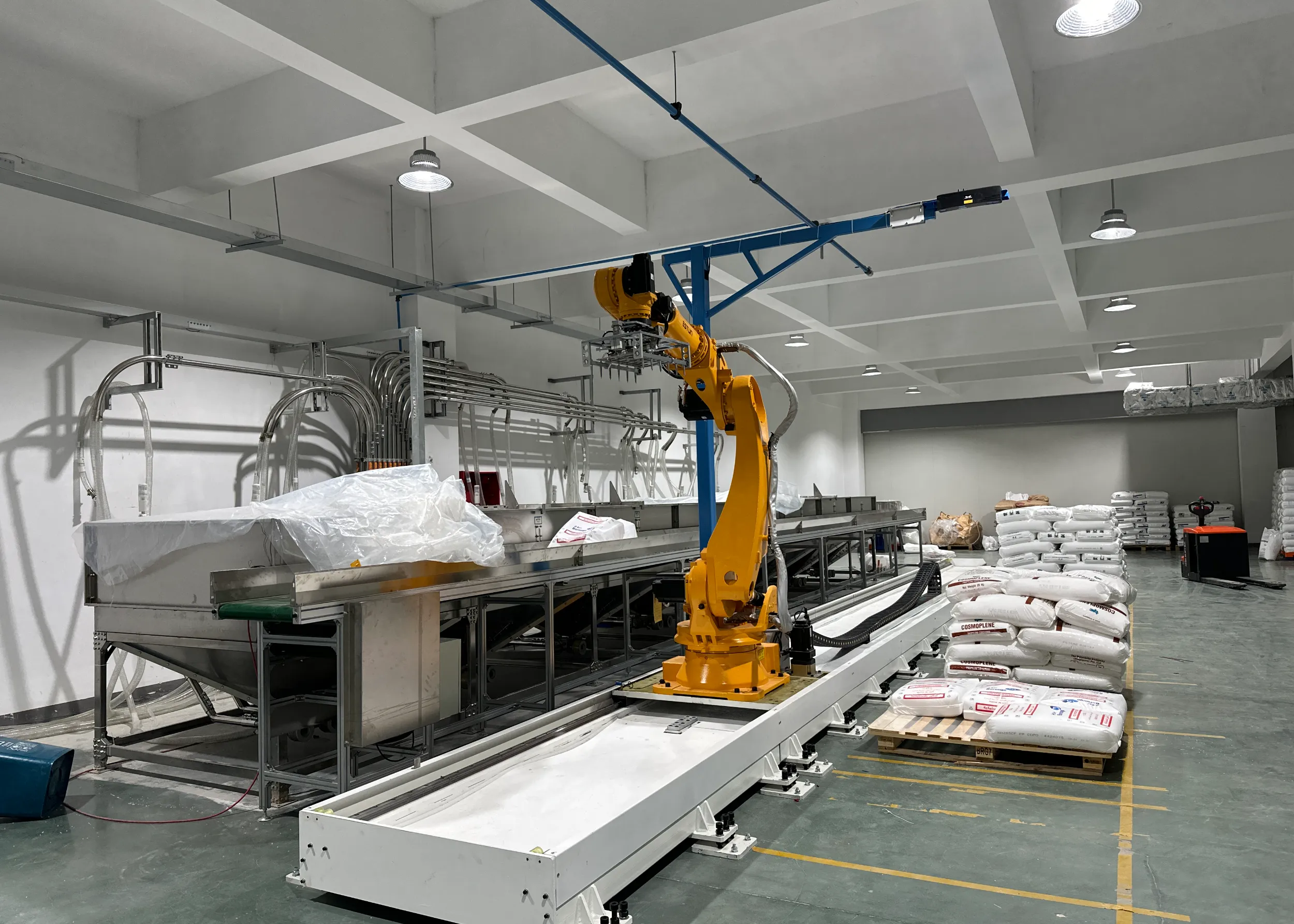 Yellow robotic arm with multi-gripper end effector handles polymer pellet bags on conveyor line. - DONGGUAN NIASI PLASTIC MACHINE CO.,LTD. | Cpsemarketplace

