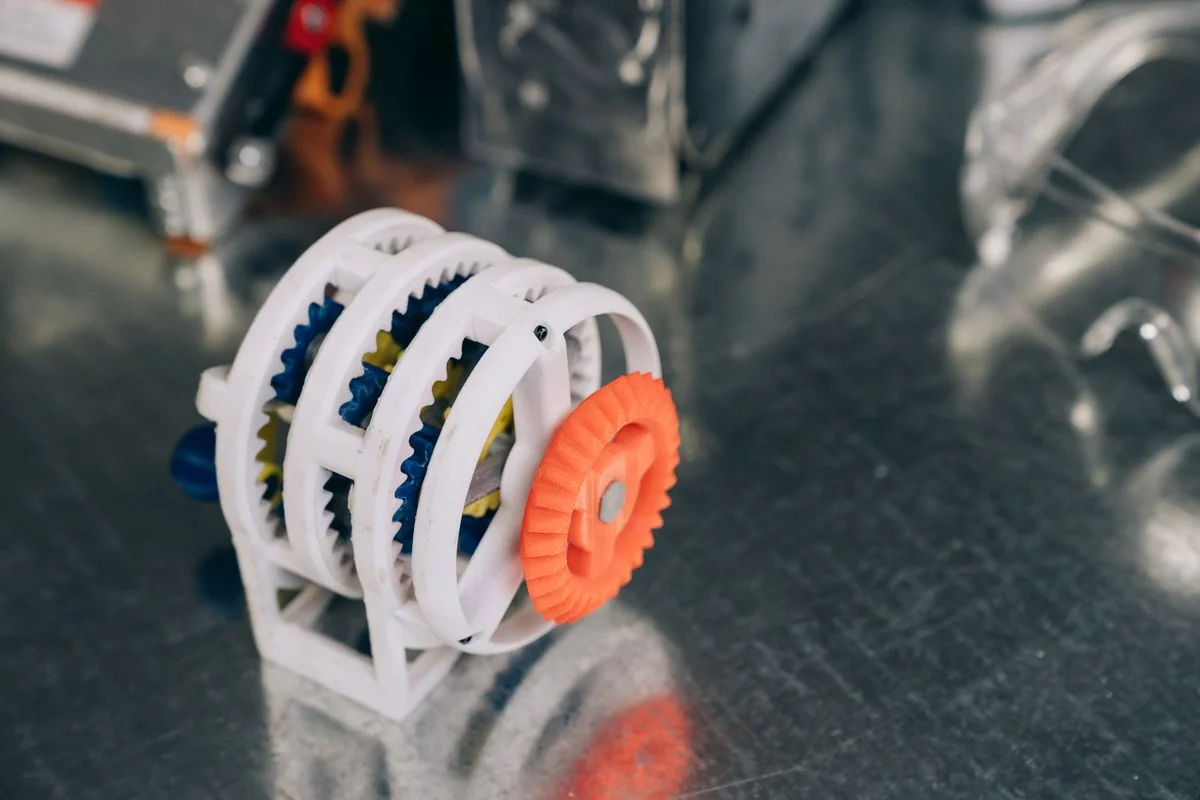 Precision-engineered assembly of white and orange plastic gears and structural components. - Pexels

