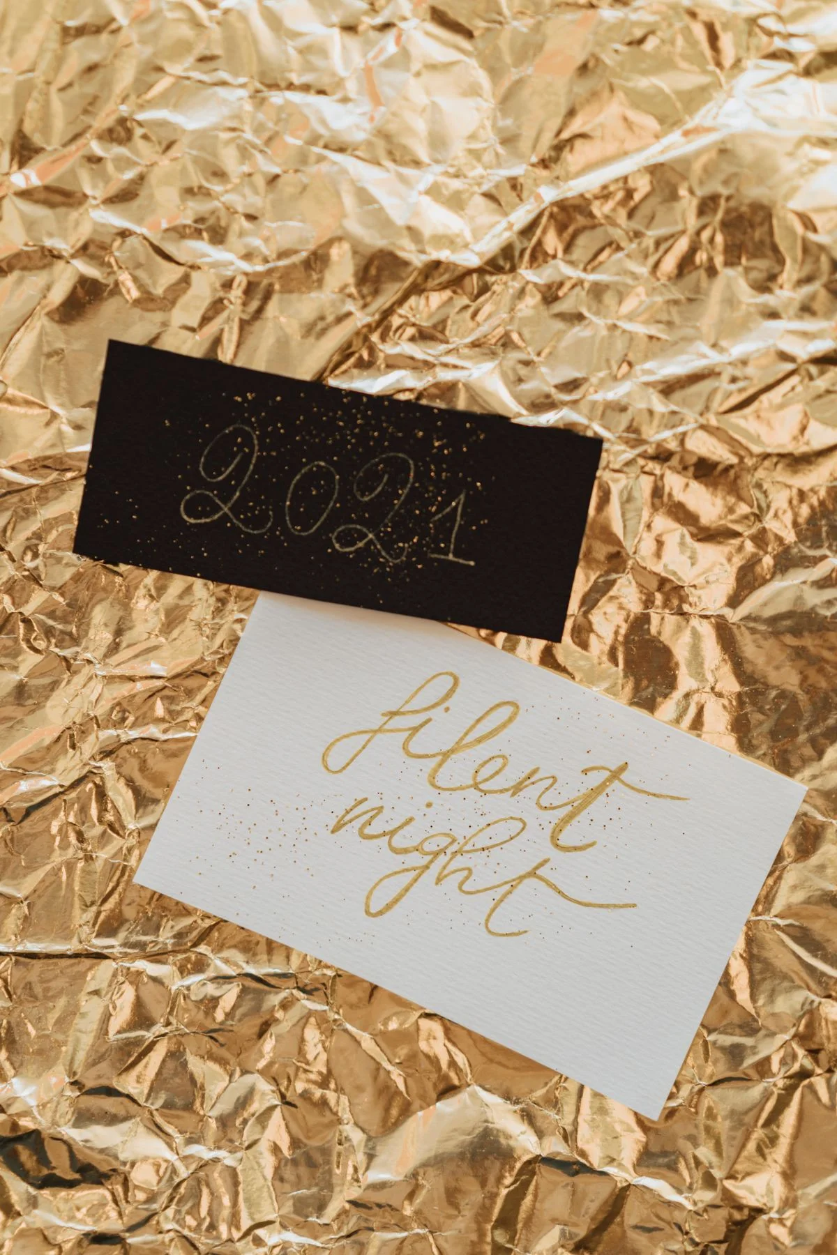 Cartes estampées à la feuille d'or avec lettrage métallique réfléchissant sur surfaces texturées. - Pexels