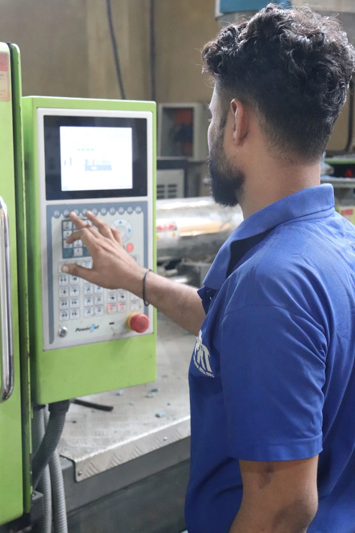 L'opérateur contrôle la machine industrielle de moulage par injection via le panneau IHM à écran tactile. - Pexels

